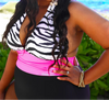 Woman in a zebra print top and pink bikini bottom with sunglasses on a beach.