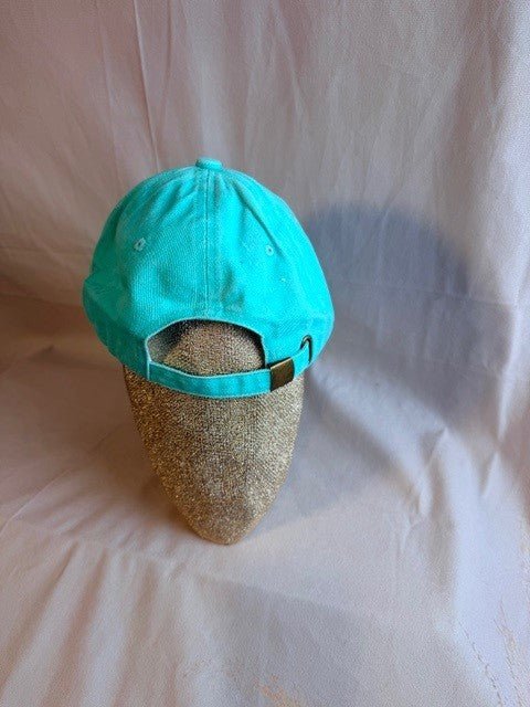 Turquoise cap on a mannequin head against a plain background