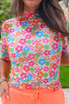 Person wearing a colorful floral patterned shirt with pink pants outdoors.