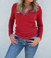 Person wearing a red long-sleeve top and blue jeans against a white background