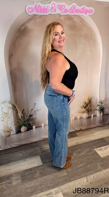 Woman in black top and blue jeans standing in a decorated room with 'Nikki & Co Boutique' sign.