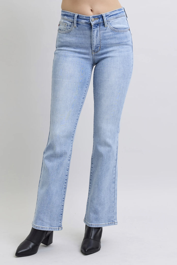 Light wash blue denim jeans with a straight-to-flare leg, shown on a model wearing black pointed-toe ankle boots against a light gray studio background.