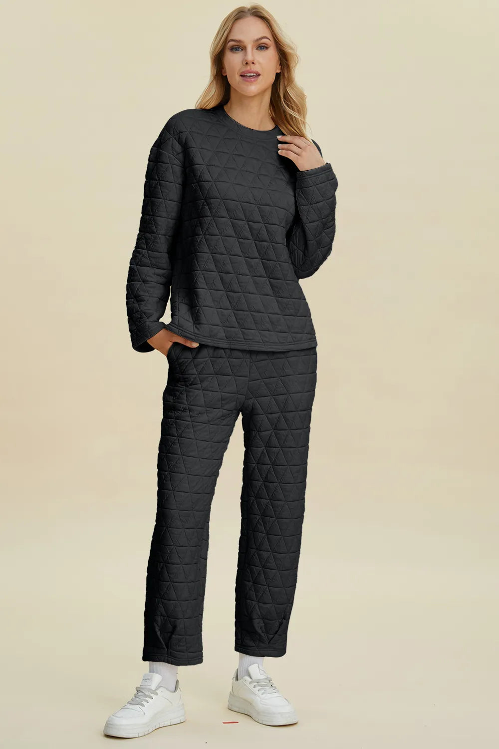 Woman wearing a dark gray quilted outfit on a beige background