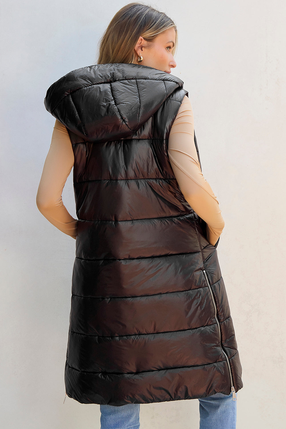 Woman wearing a long black puffer vest against a light background