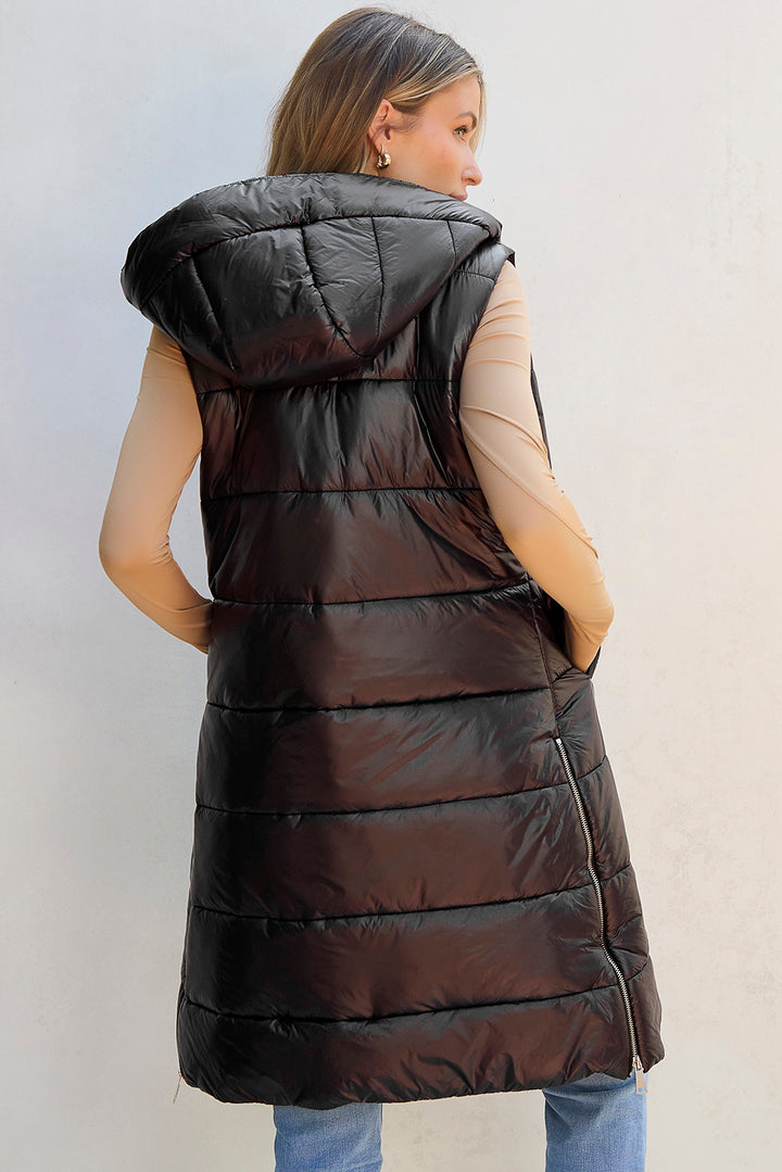 Woman wearing a long black puffer vest against a light background