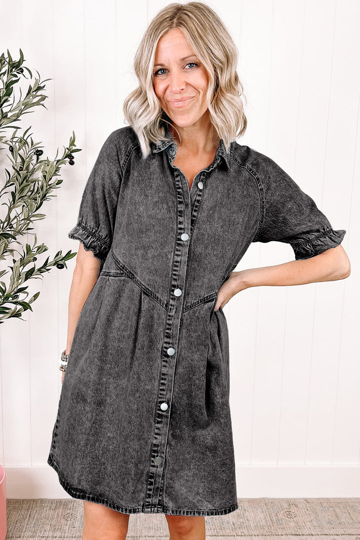 Woman wearing a gray denim dress standing indoors with a plant in the background