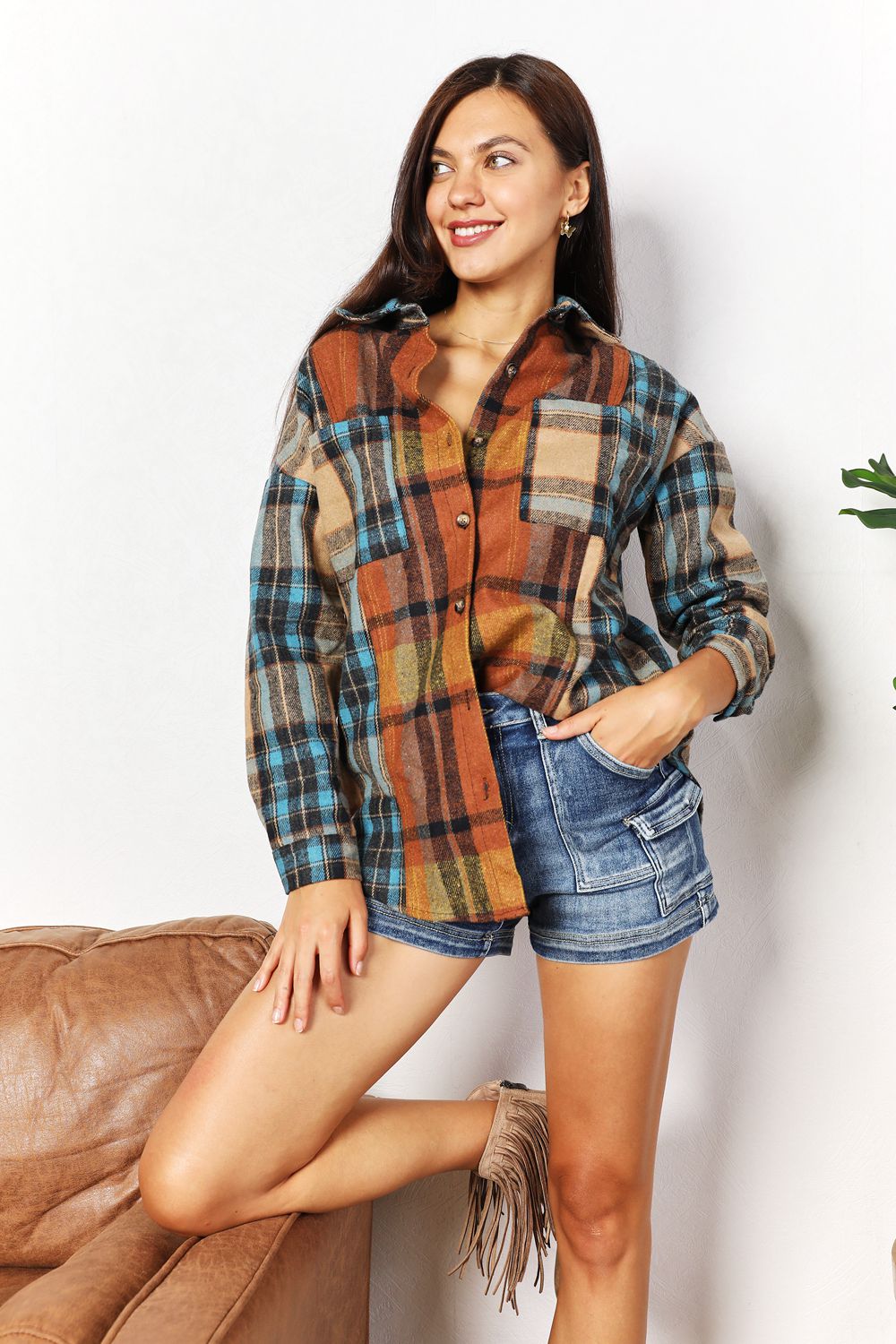 Woman wearing a plaid shirt and denim shorts against a white background