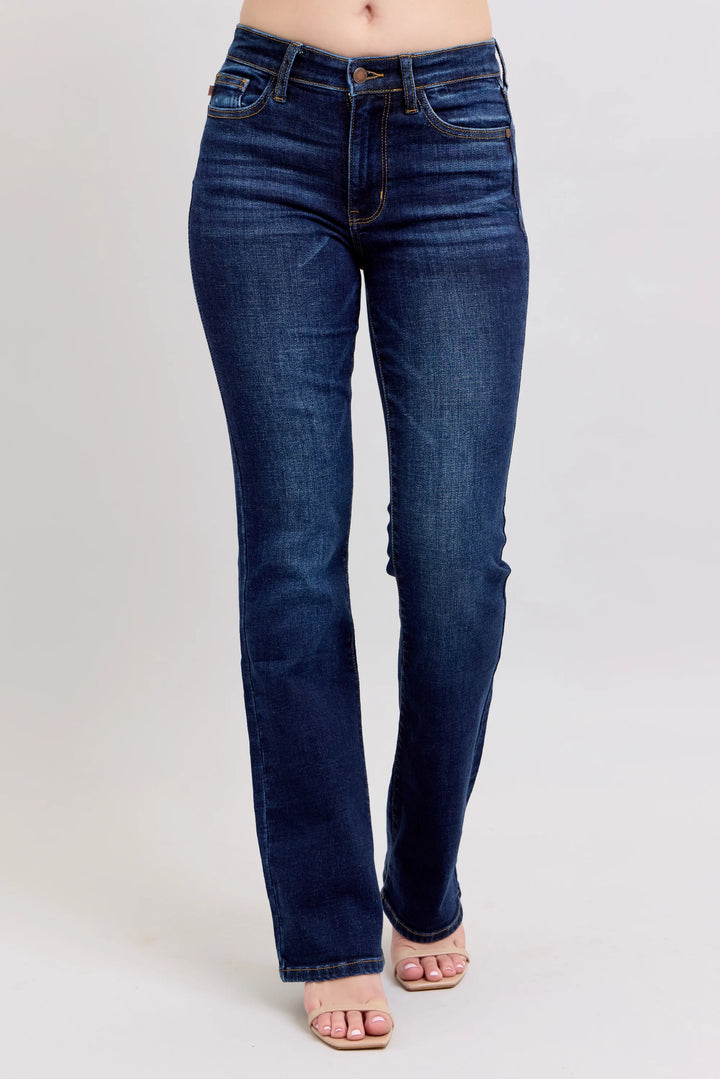 A person wearing dark blue straight-leg denim jeans and light pink sandals, shown from the waist down against a light gray studio background.