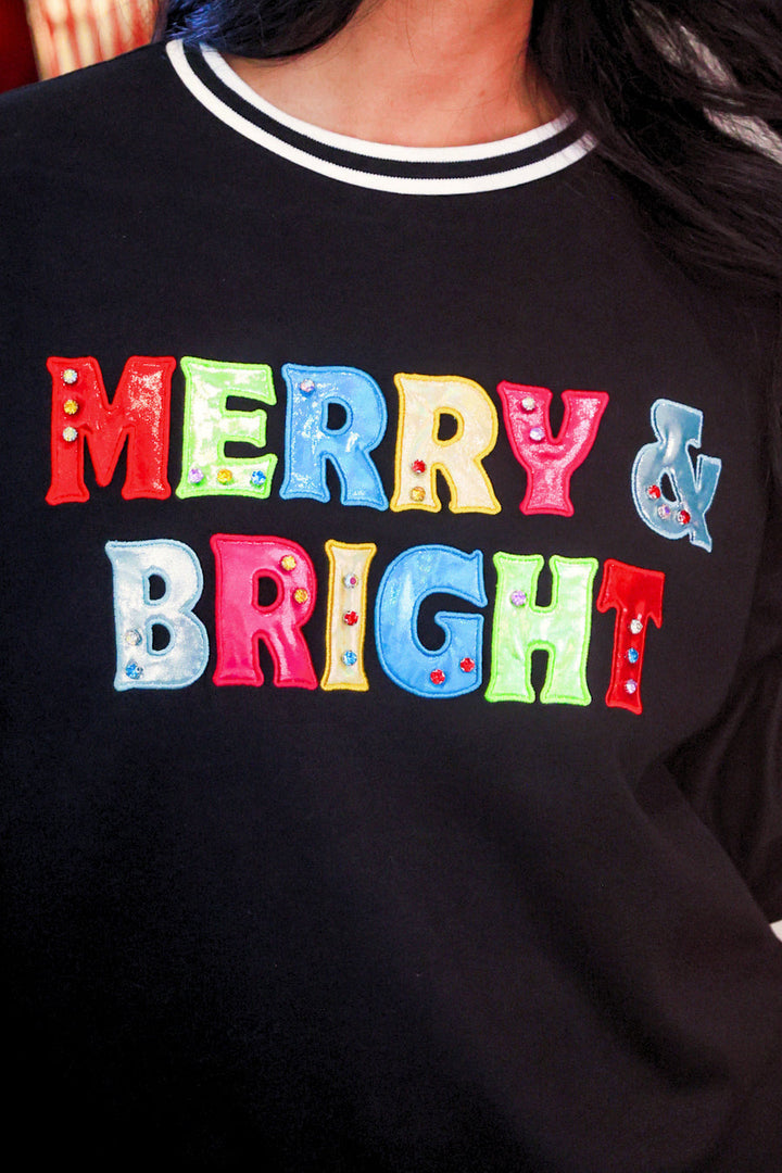 A close-up of a person wearing a black crewneck sweatshirt with &