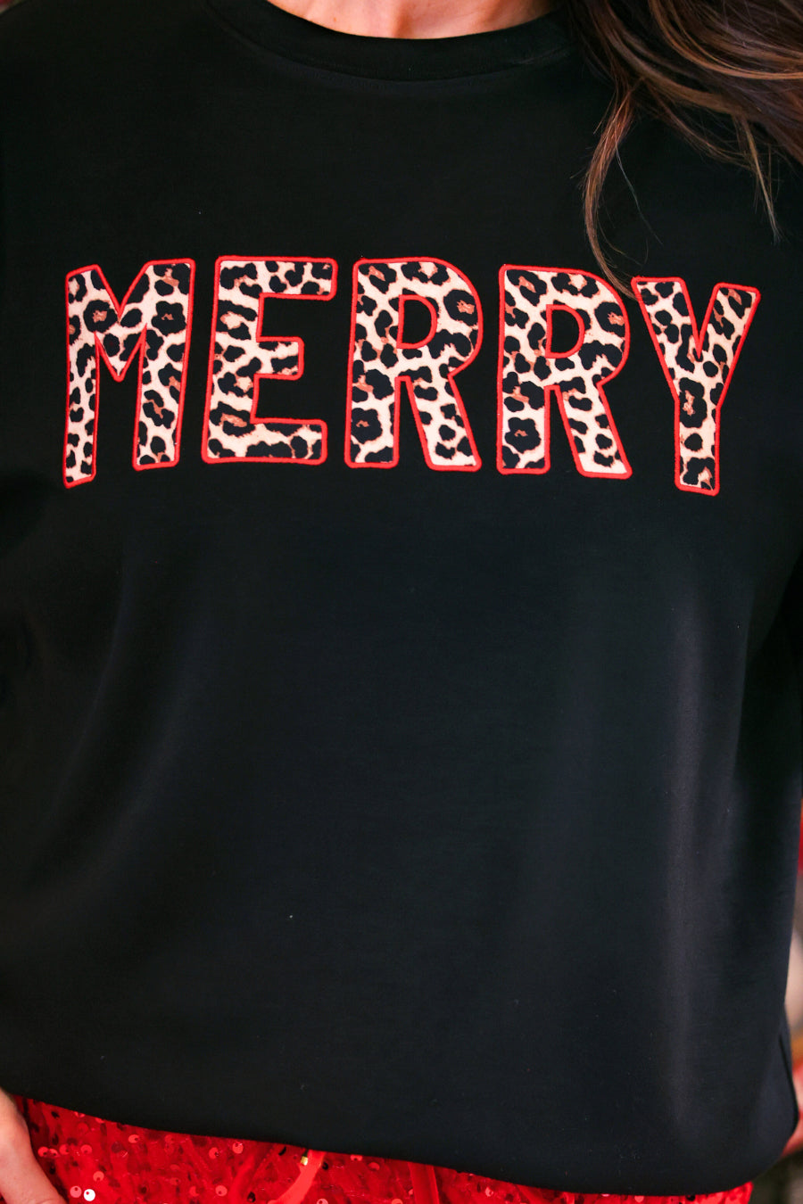A close-up of a black crewneck sweatshirt featuring the word &