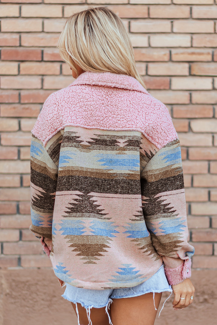 Person wearing a pink and patterned cardigan against a brick wall