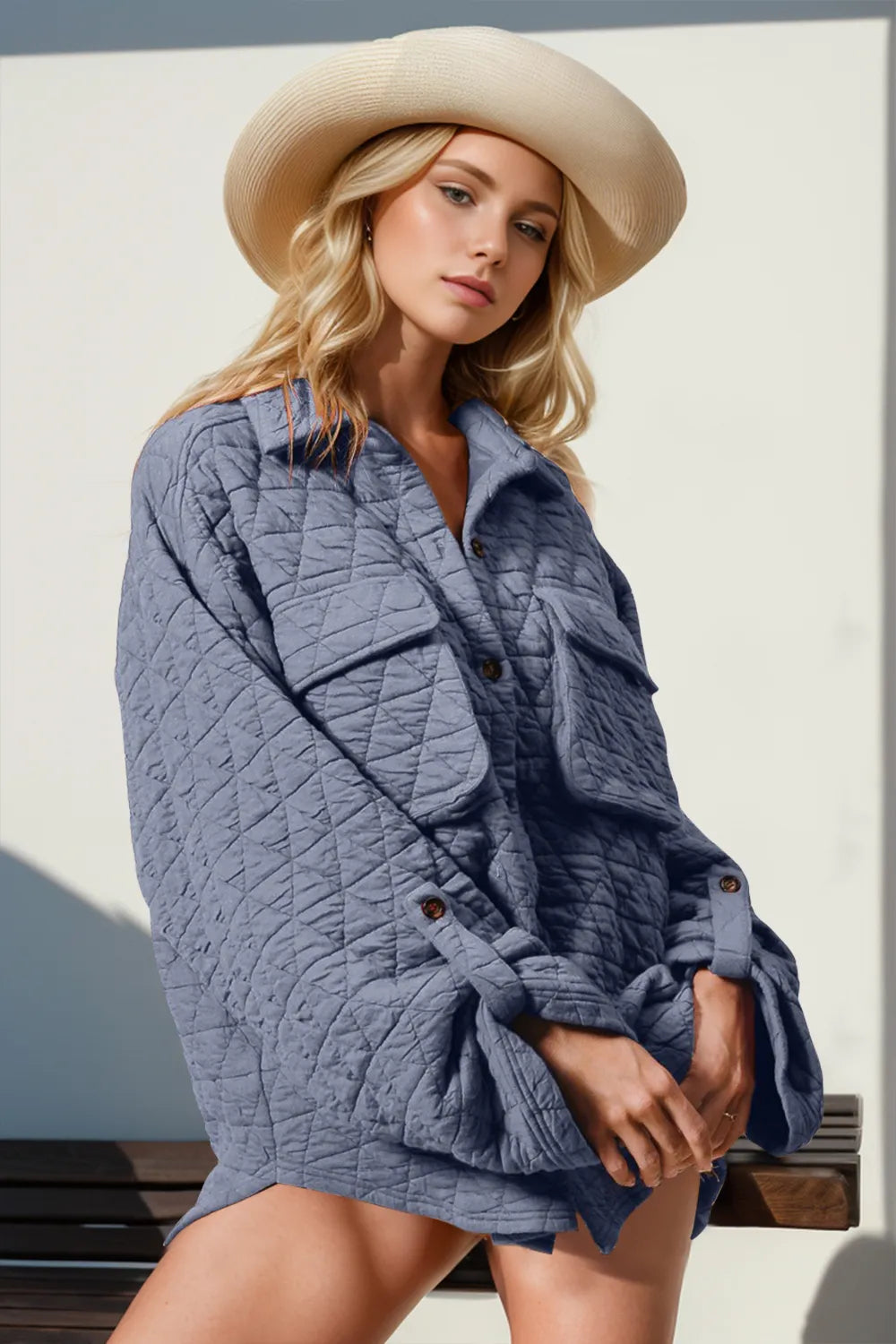Woman wearing a blue quilted jacket and beige hat against a light background