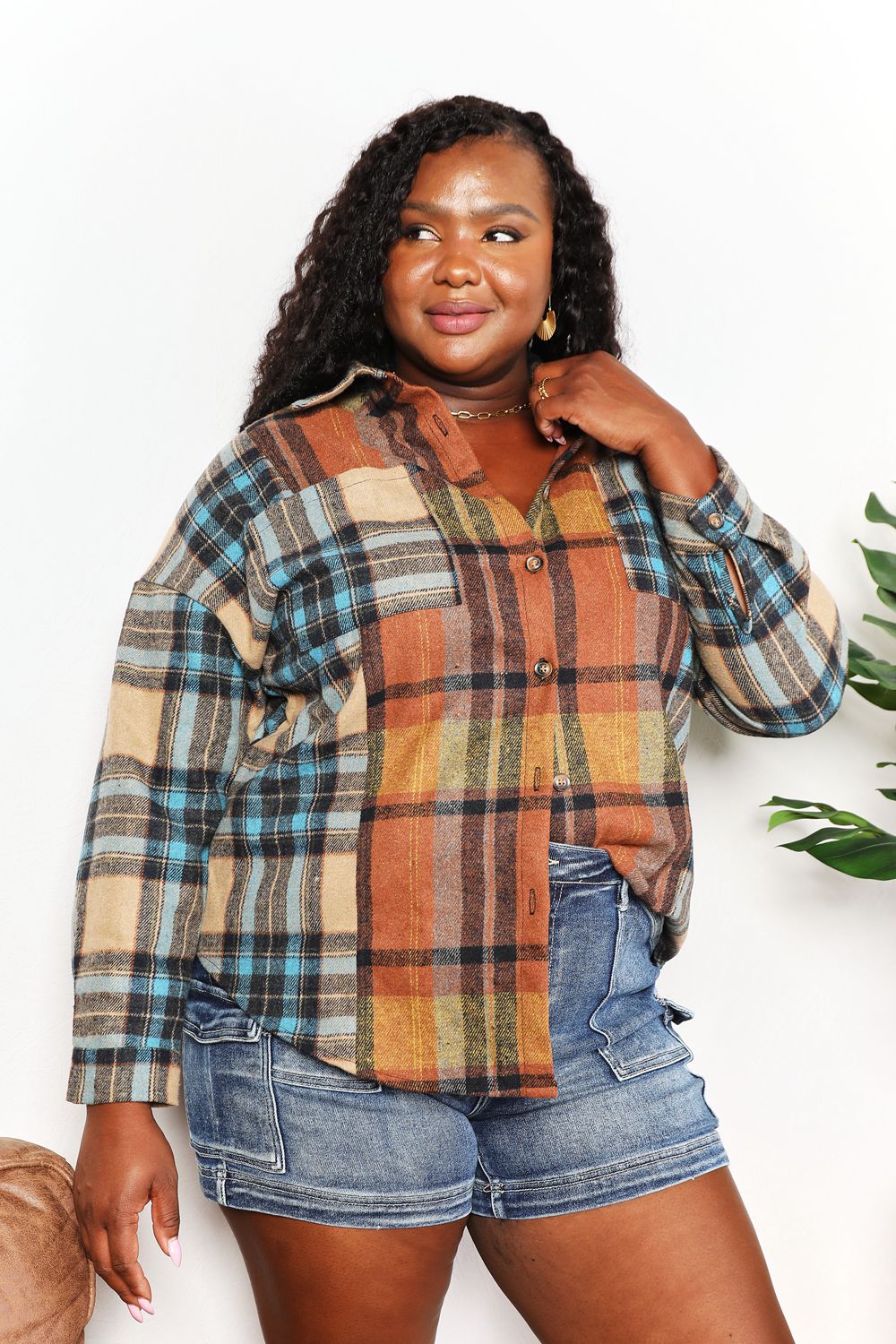 Woman wearing a plaid shirt and denim shorts against a white background