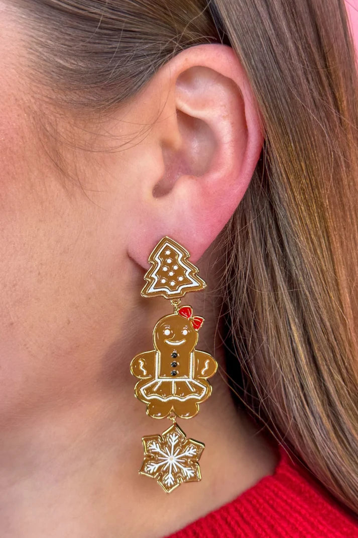Woman wearing gingerbread man earrings.