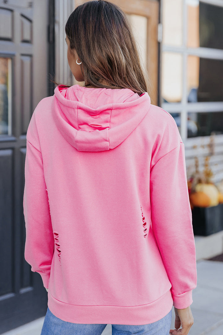 Person wearing a pink hoodie with a blurred background