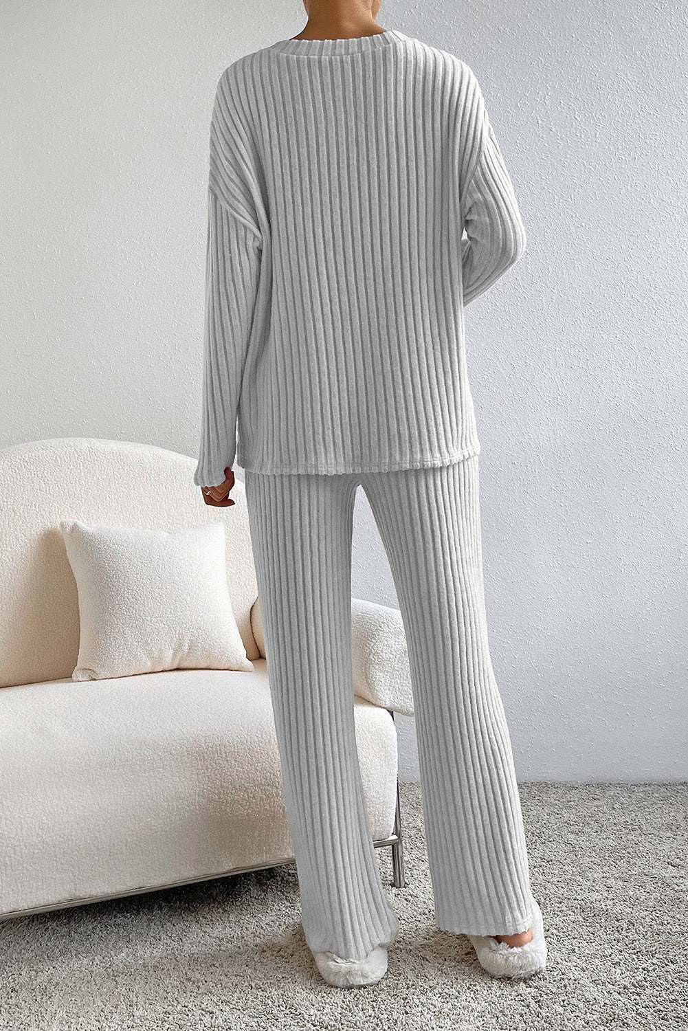 Person wearing a gray ribbed lounge set in a living room setting.