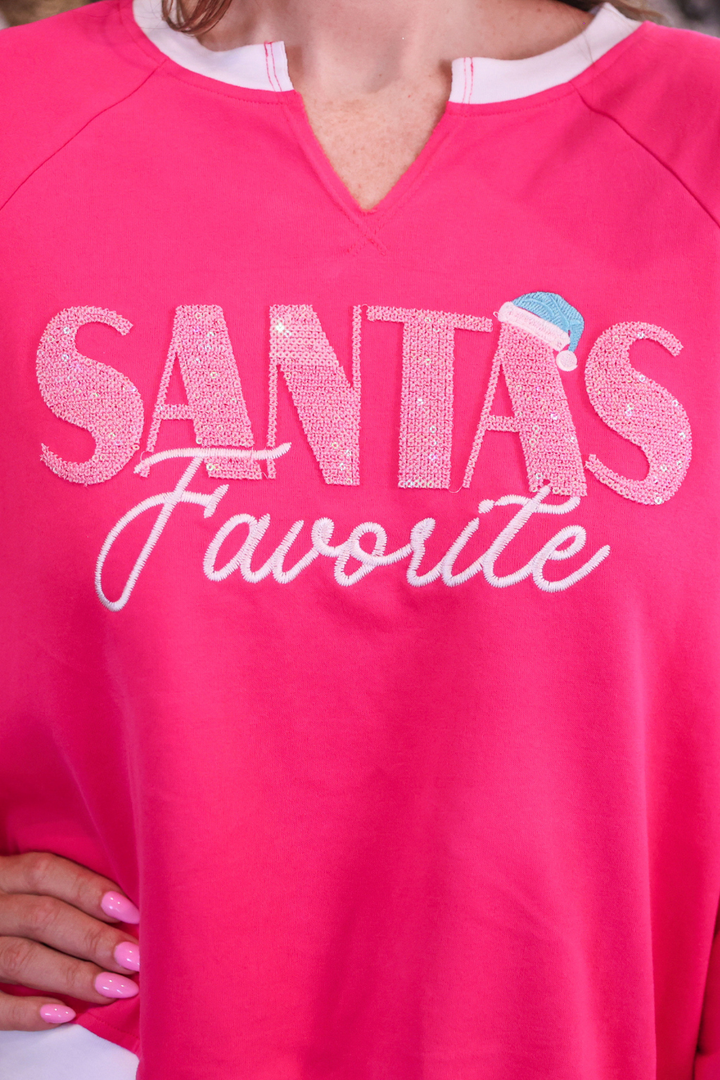 A close-up of a bright pink V-neck sweatshirt featuring the text &