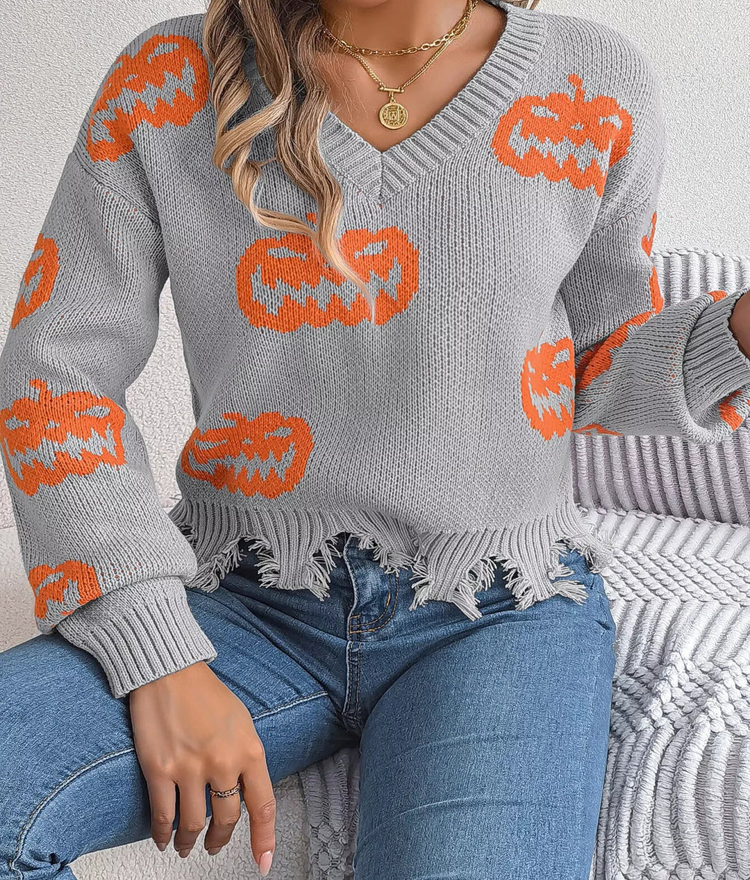 Women wearing grey sweater with pumpkins on it while sitting