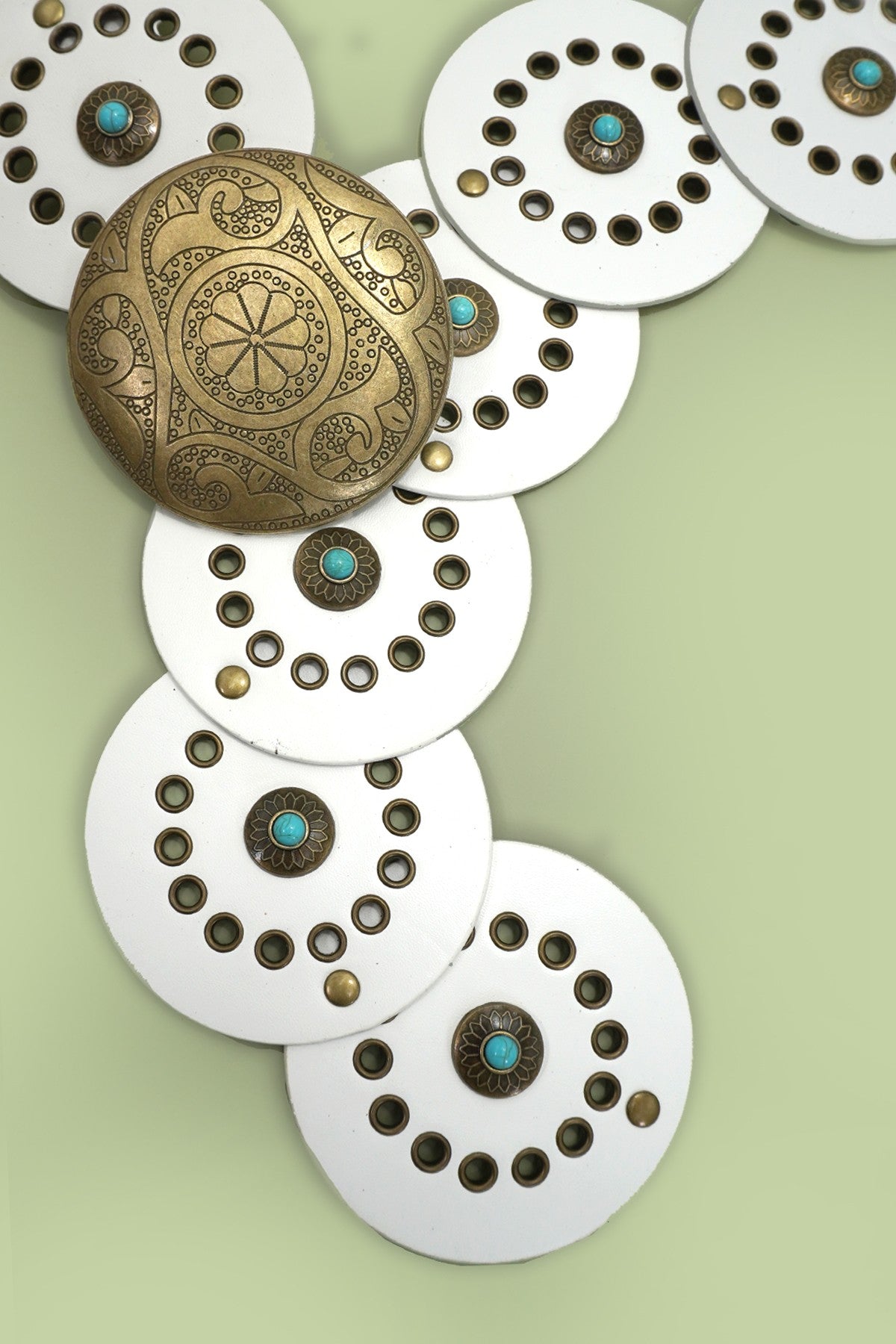 Decorative metal buttons with intricate designs on a light green background