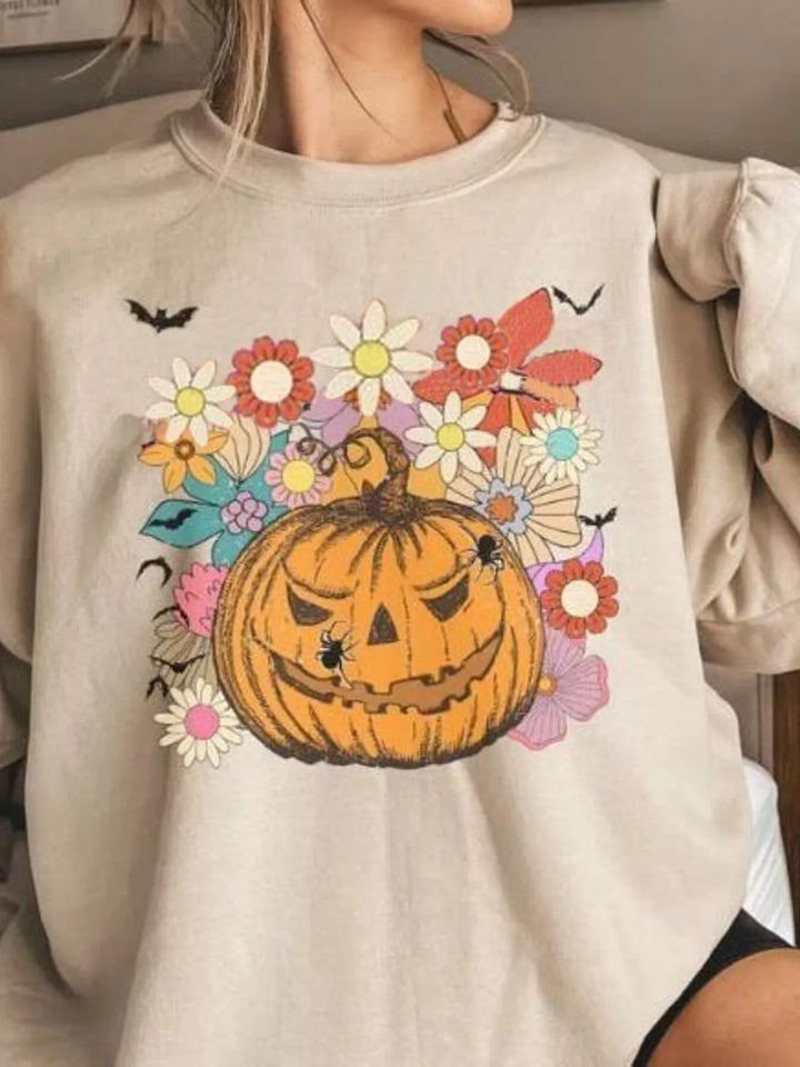 Women wearing tan sweatshirt with a pumpkin, flowers, and bats centered on the top