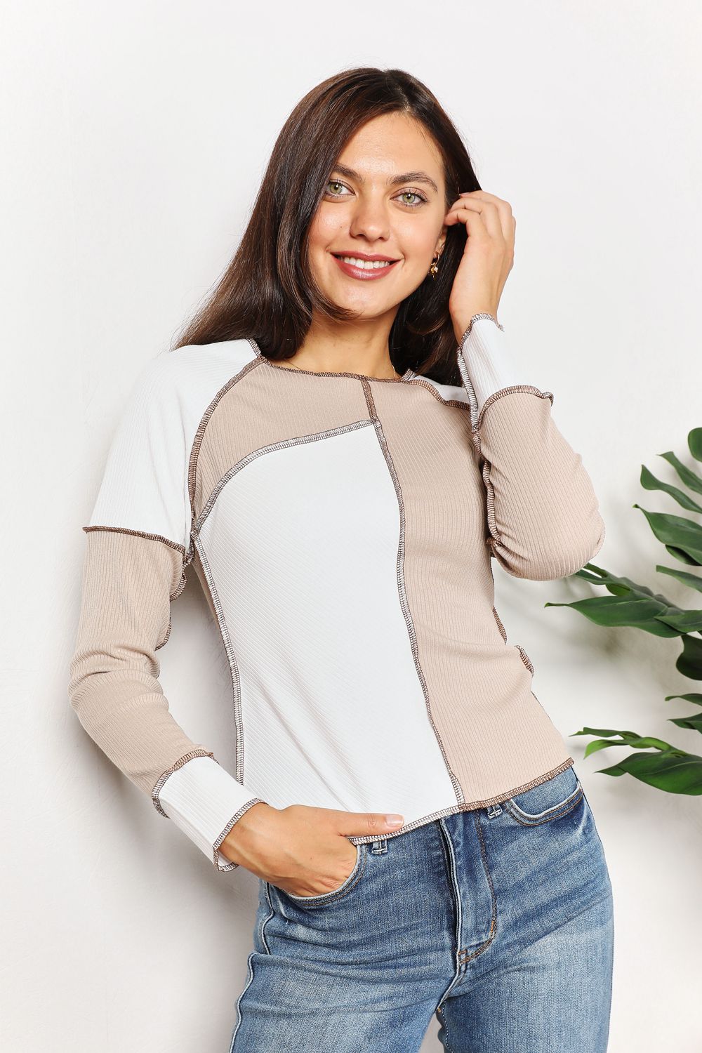Woman wearing a color-blocked long-sleeve top with a plain background