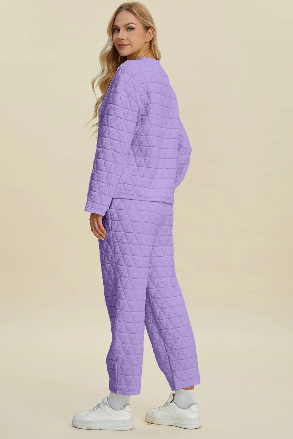 Woman wearing a purple quilted outfit on a beige background