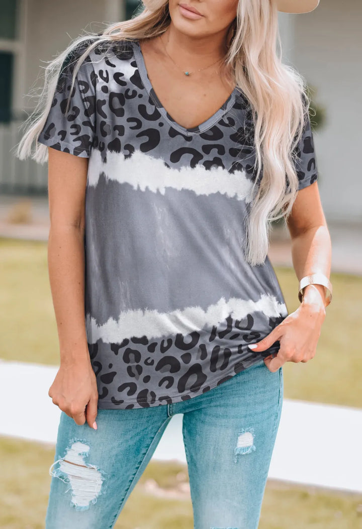 Woman wearing a gray tie-dye shirt with leopard print accents and light blue jeans.