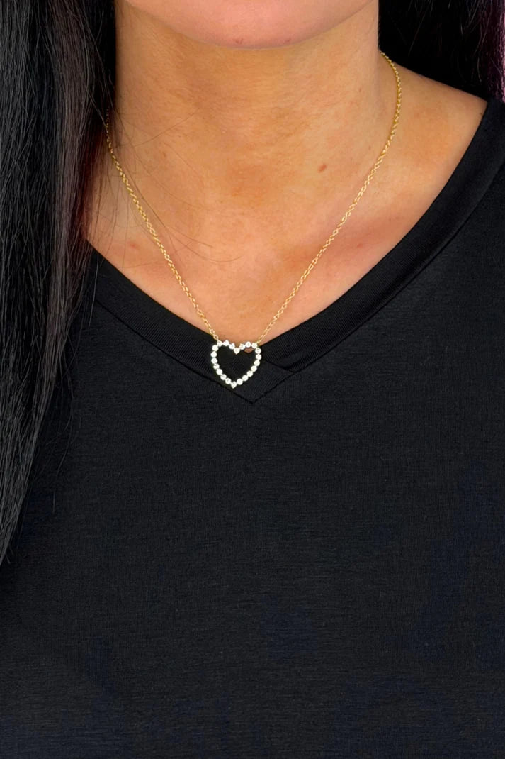 Woman wearing a gold chain with a single heart at the center.