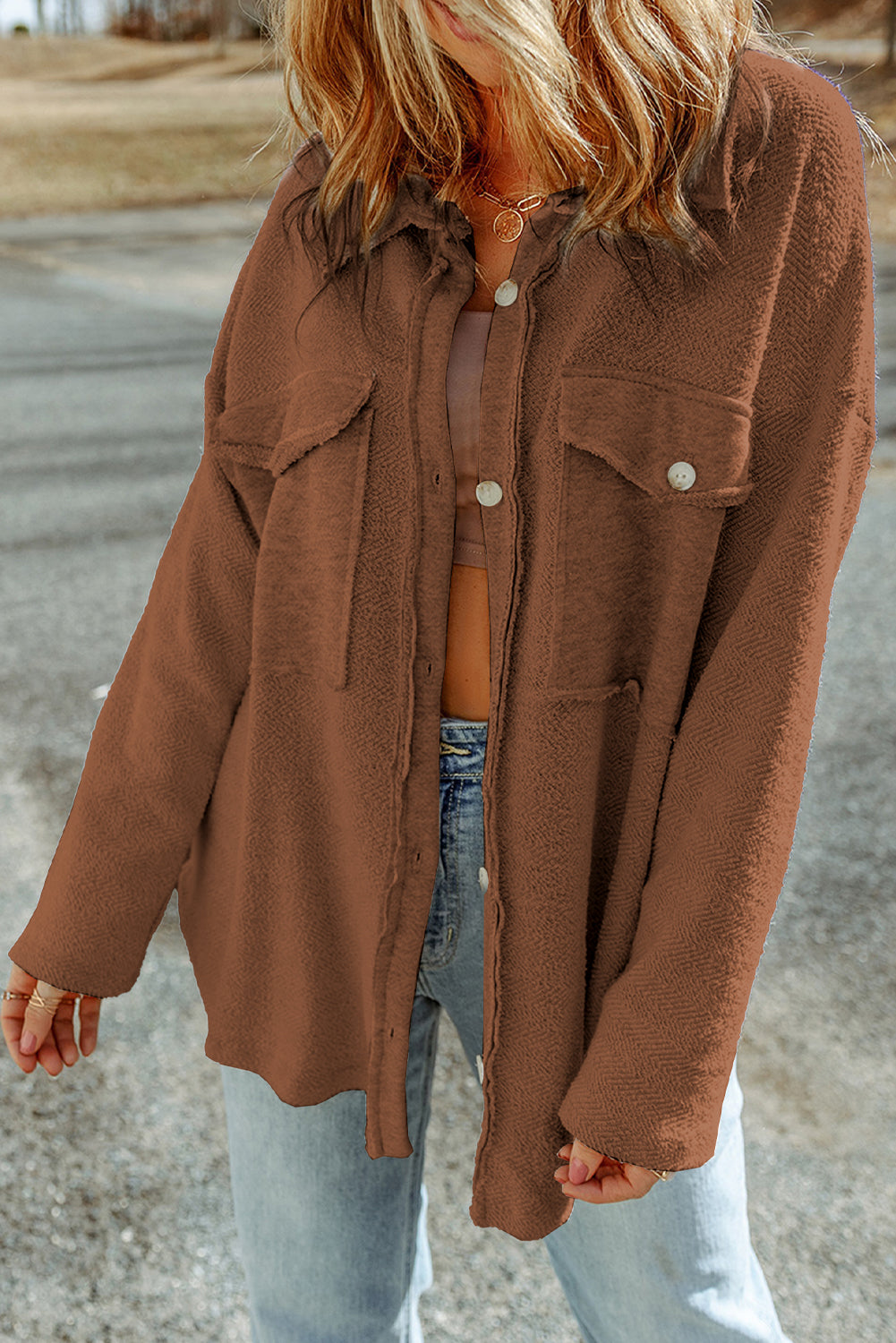 Person wearing a brown jacket and light blue jeans on a road background