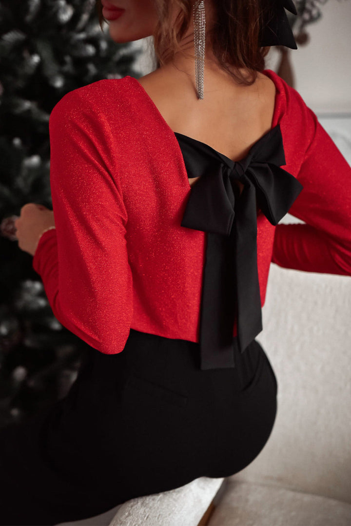 Red blouse with a black bow detail on the back, worn by a person sitting.
