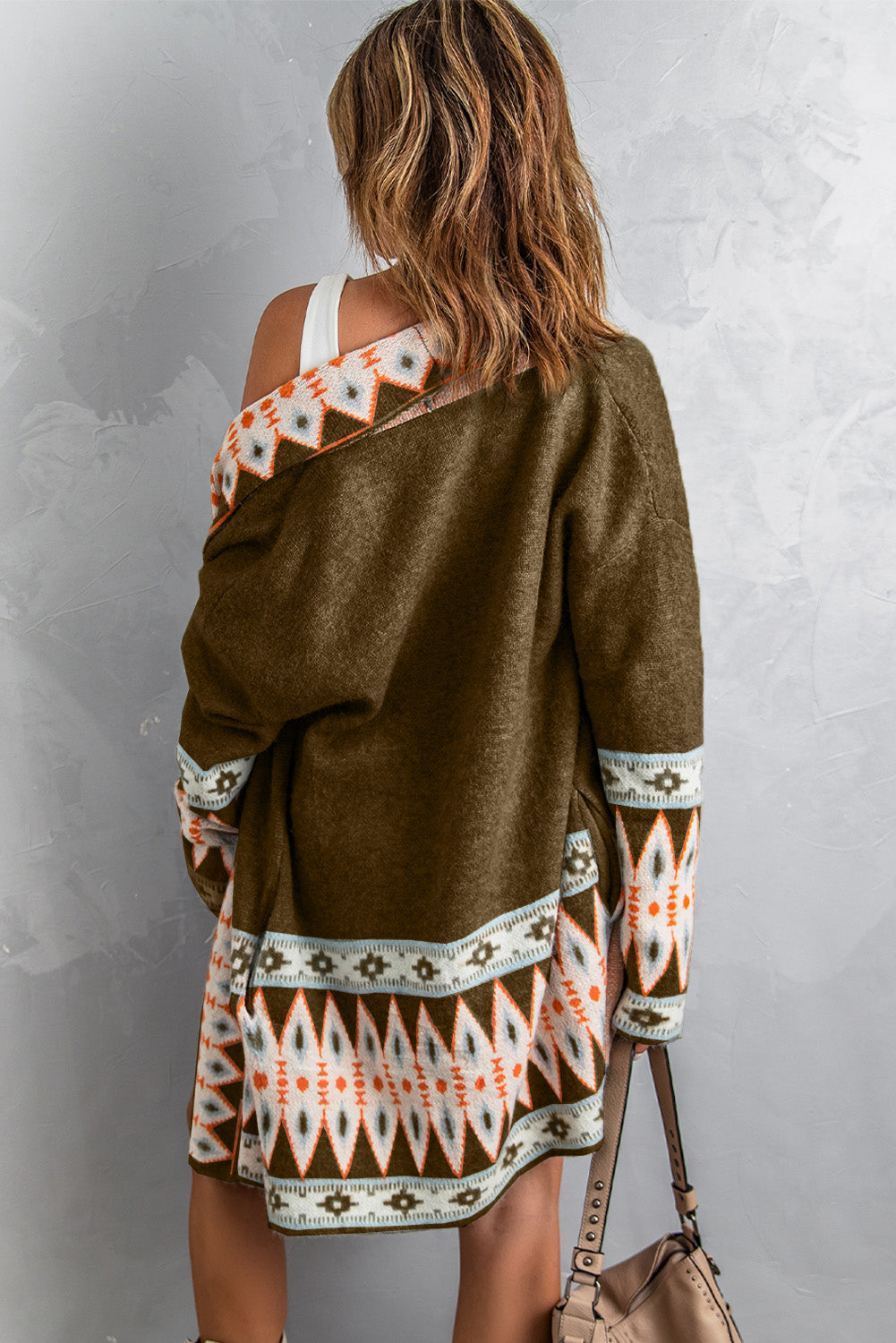 Woman wearing a brown patterned cardigan with a plain background