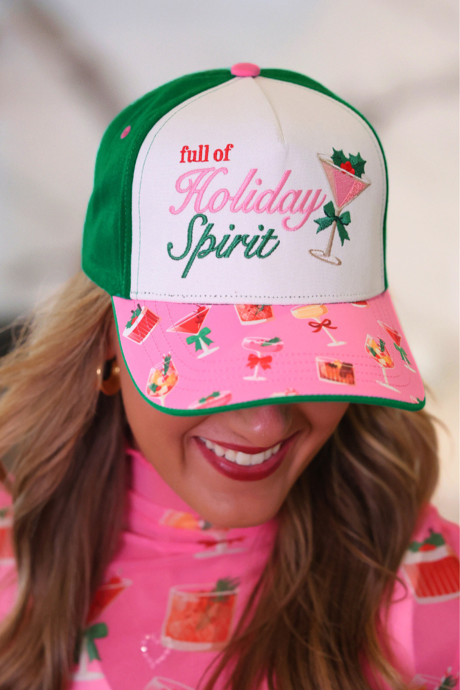 A woman wearing a green and white trucker-style baseball cap with &