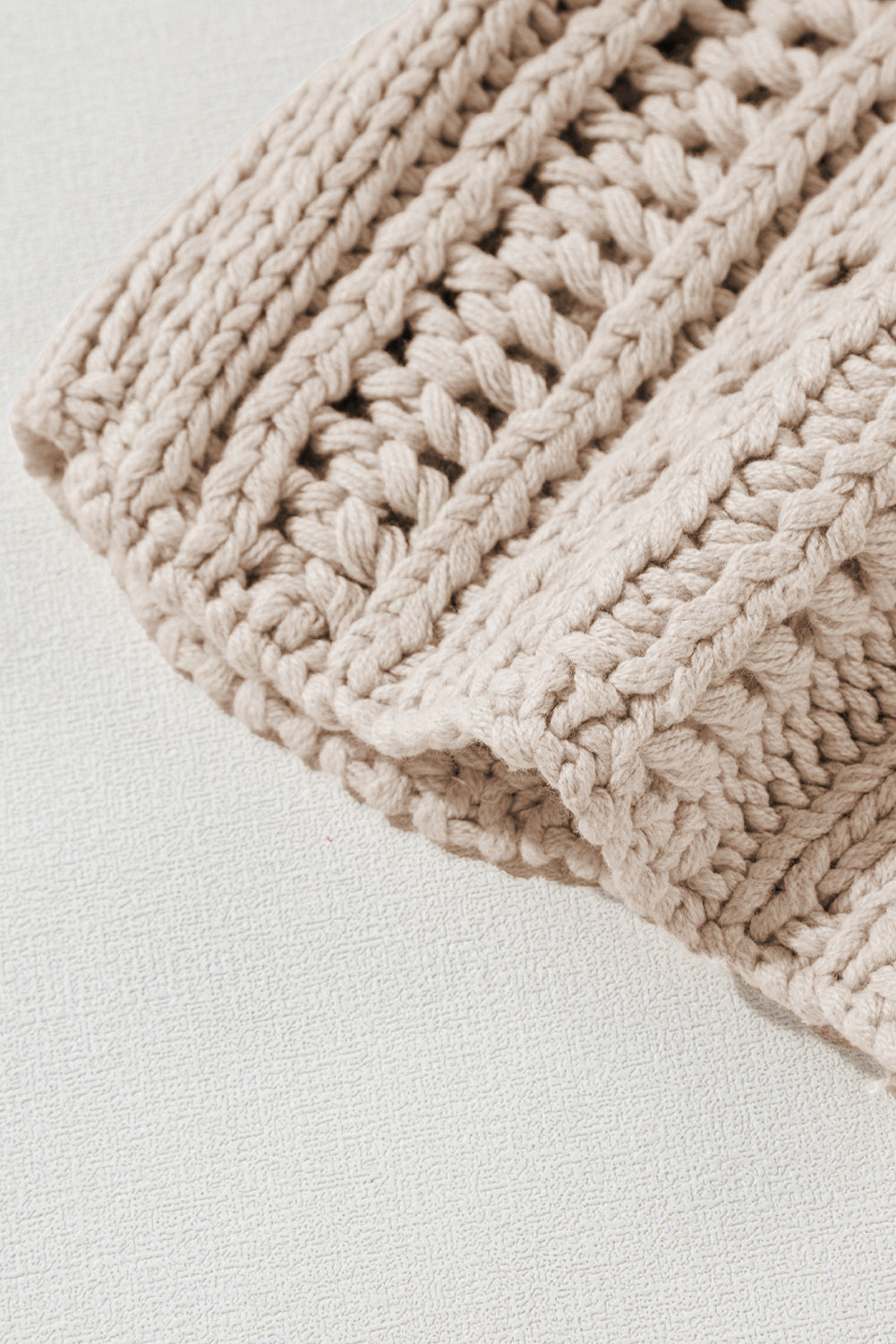 Close-up of a beige knitted blanket on a light gray background