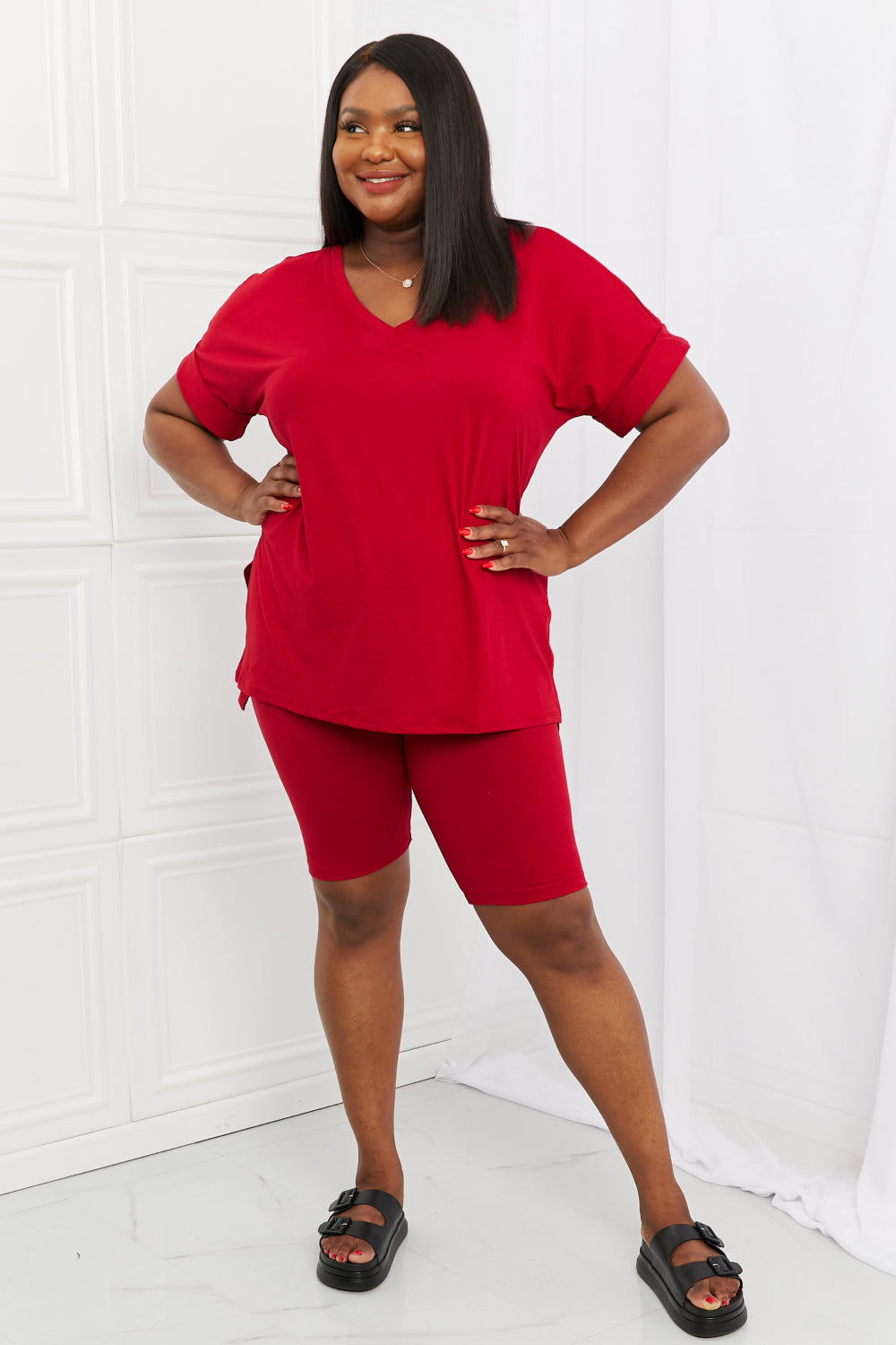 Woman wearing a burgundy outfit standing against a white background