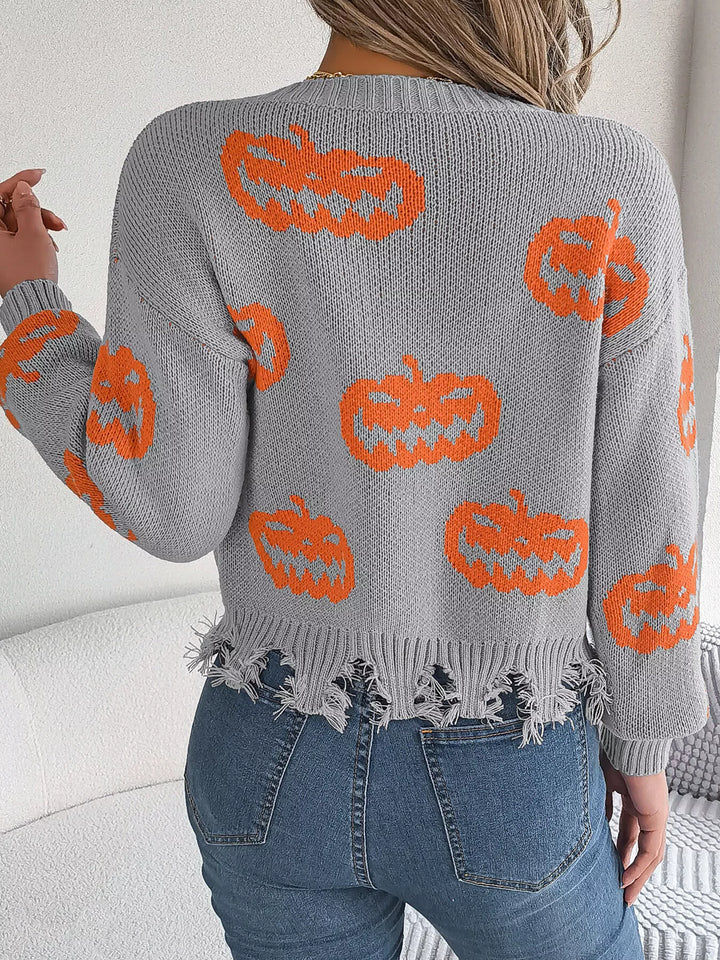 Women wearing grey sweater with pumpkins on it while facing a wall