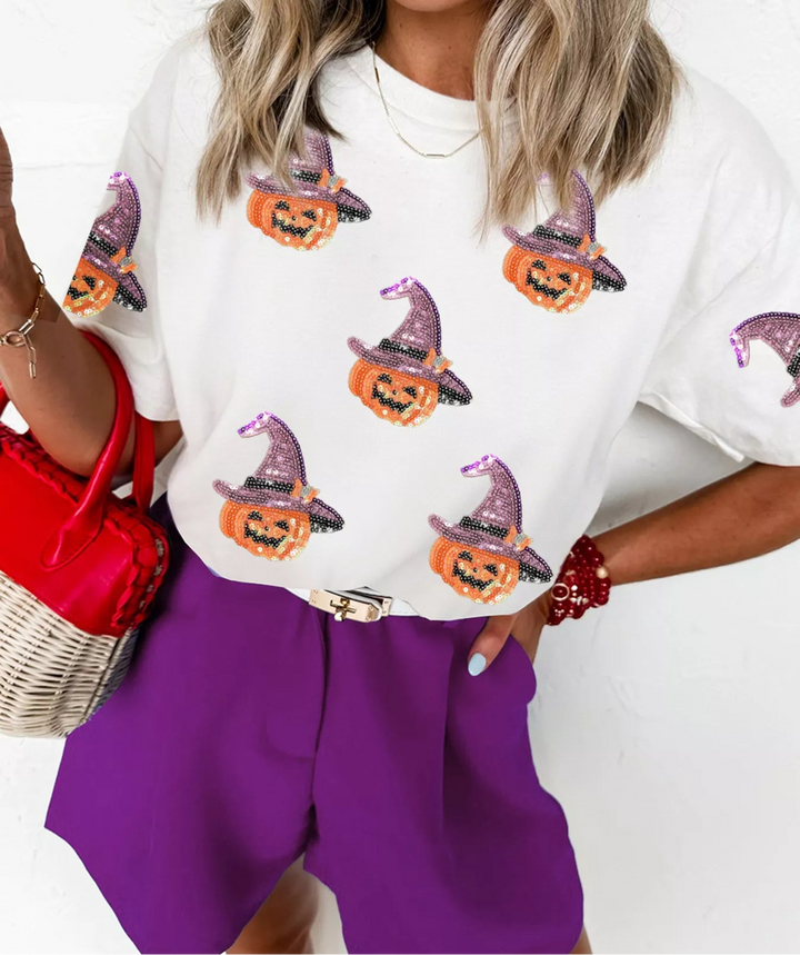 Women wearing white tee shirt with sequence pumpkins wearing a purple sequence hat