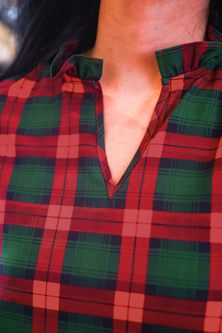 Close-up of a red and green plaid shirt worn by a model, showing the collar and chest area.