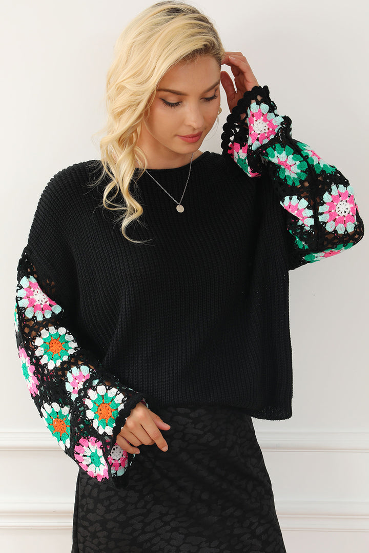 Woman wearing a black sweater with colorful floral sleeves against a white background