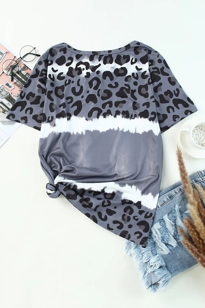 Gray leopard print top with white trim on a white surface with denim shorts and a plant.