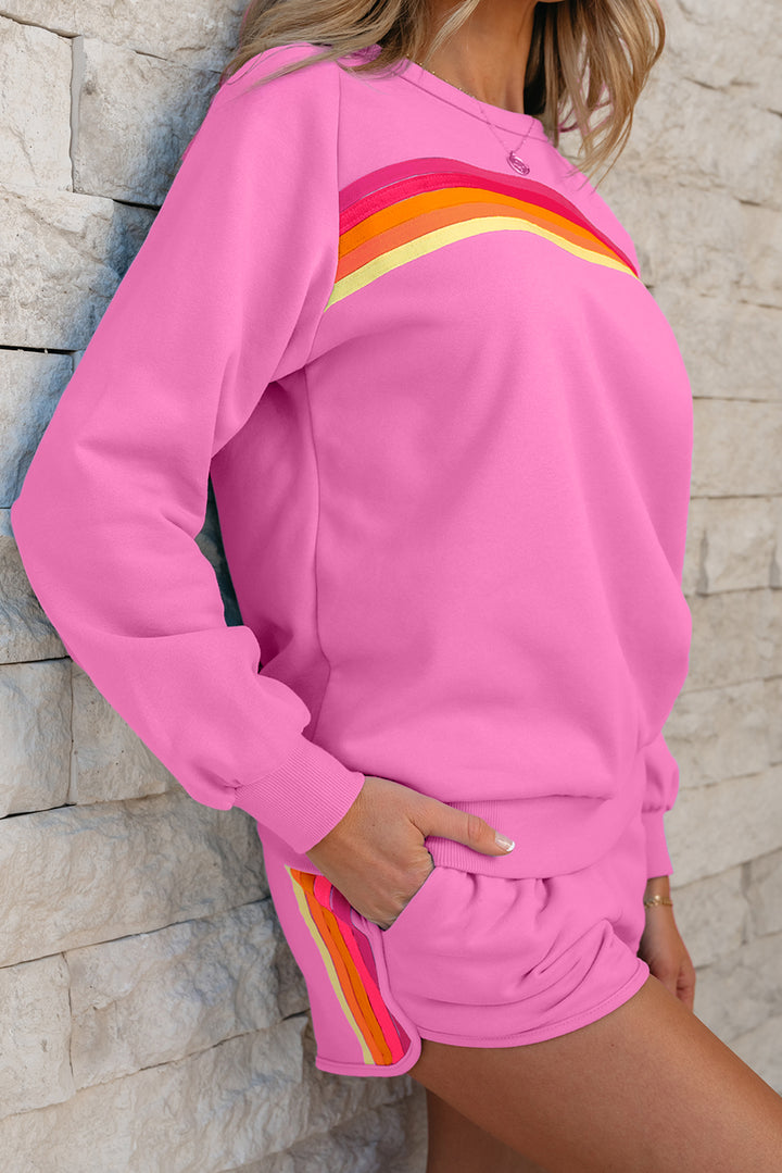 Person wearing a pink outfit with colorful stripes against a stone wall.