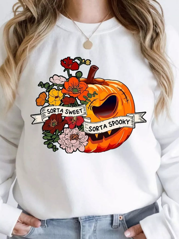 Women wearing a white sweatshirt with half of the top centers with "sort of sweet" with a flower back ground and the other half with "sort of spooky" with half of a pumpkin as the background