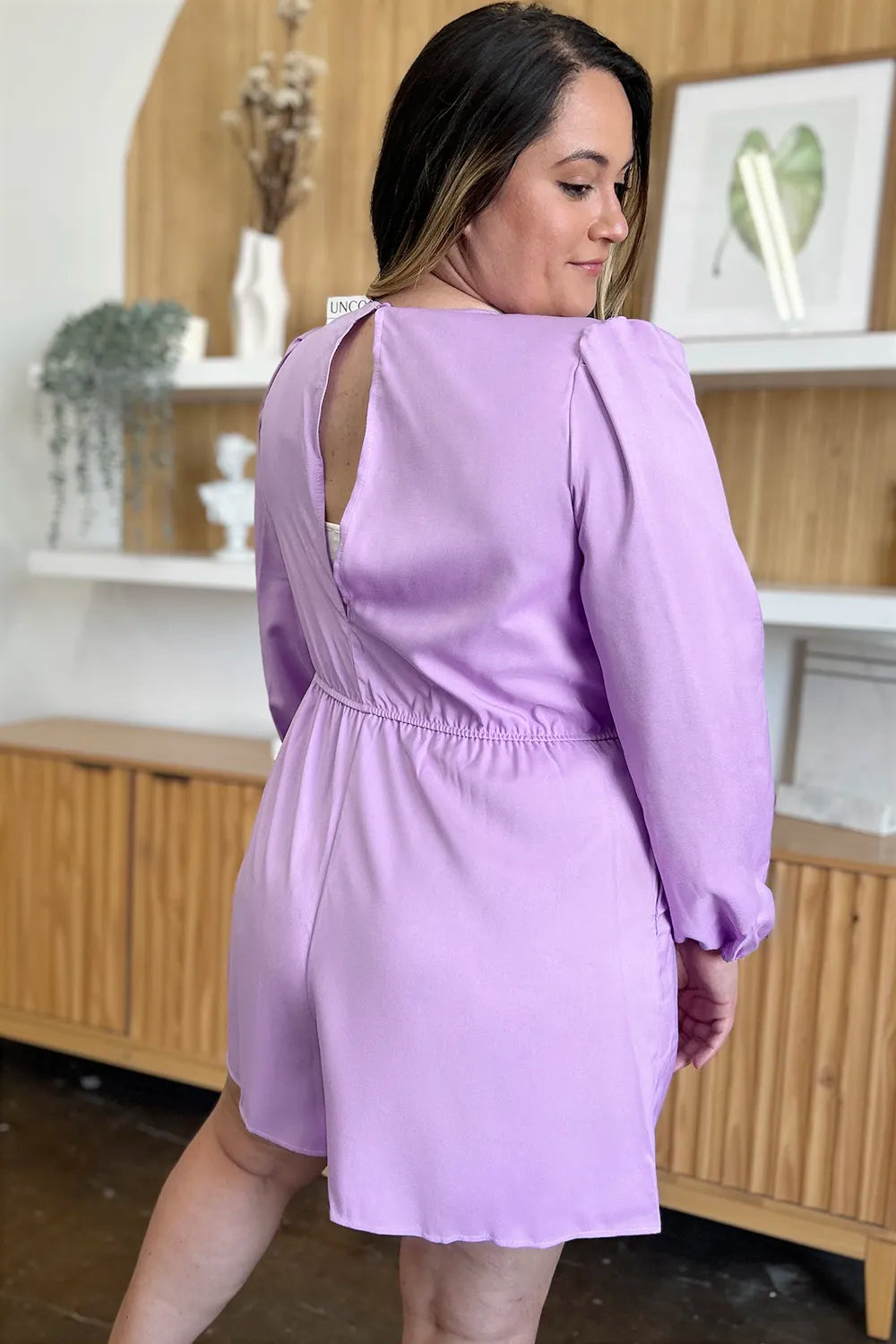 Woman wearing a light purple dress with long sleeves in an indoor setting.