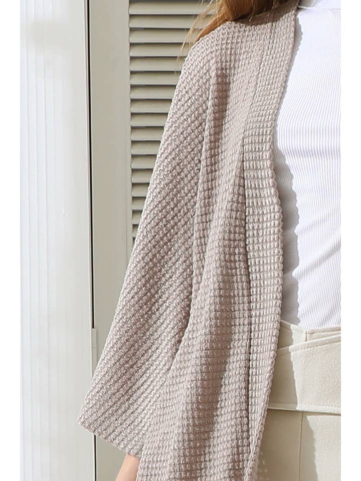 Person wearing a coconut textured cardigan a neutral background