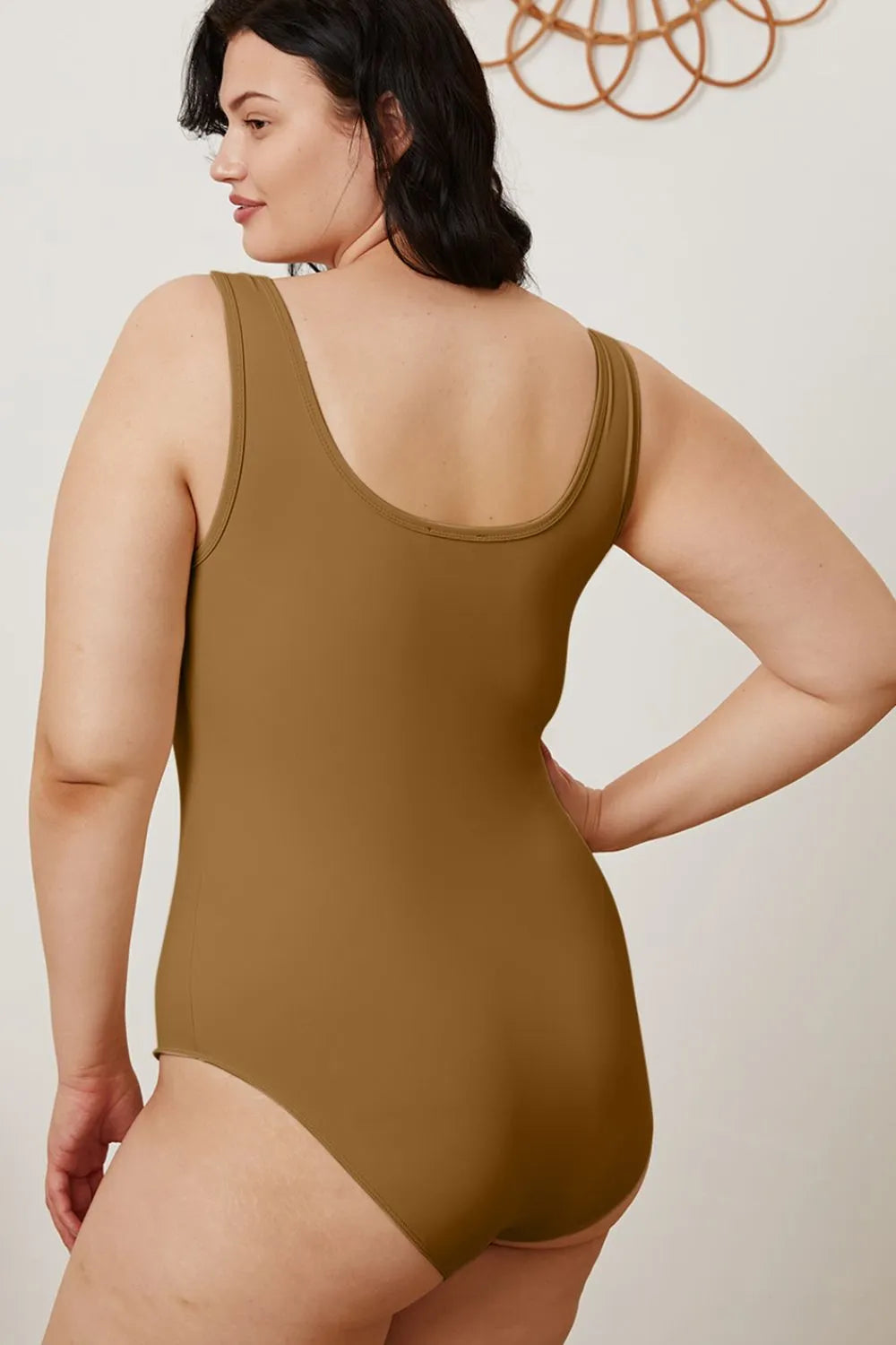 Woman wearing a brown swimsuit against a plain background
