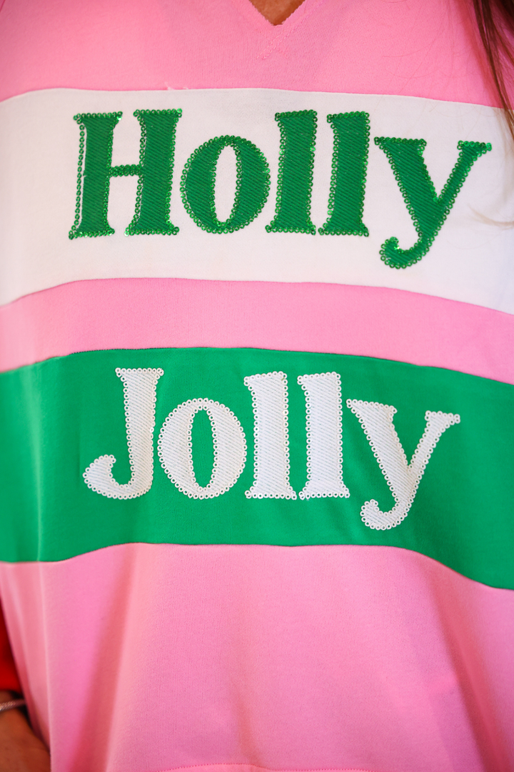 A close-up of a pink striped sweater with green and white horizontal bands. The top band is white with the word &