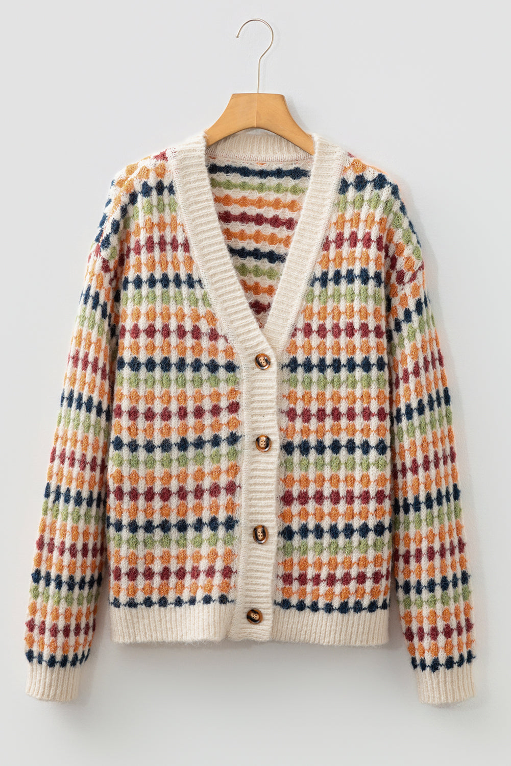 Colorful patterned cardigan on a hanger against a light background