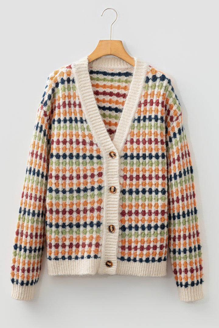 Colorful patterned cardigan on a hanger against a light background