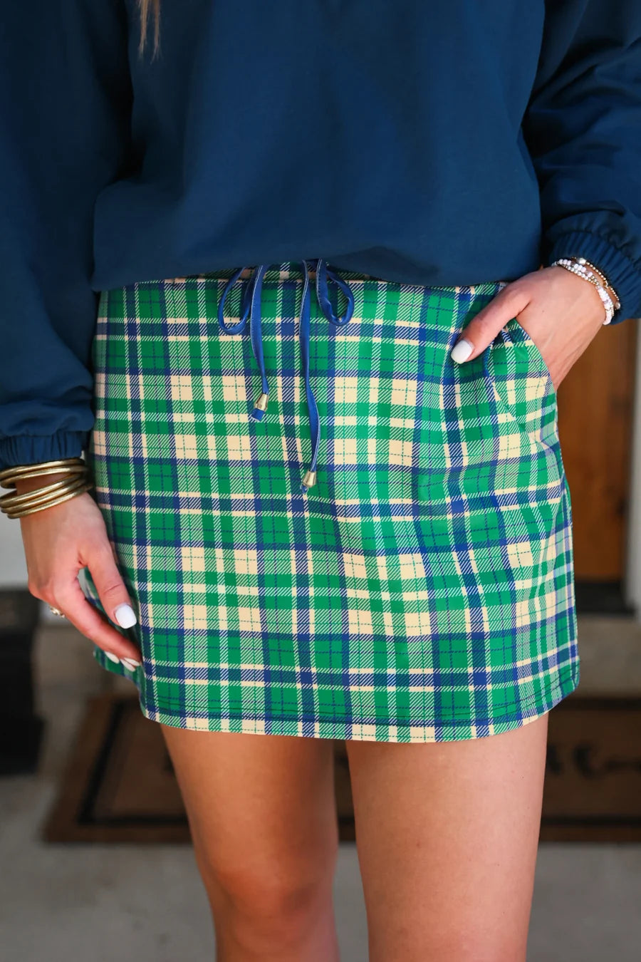 Green plaid skort worn with a blue top, blurred background