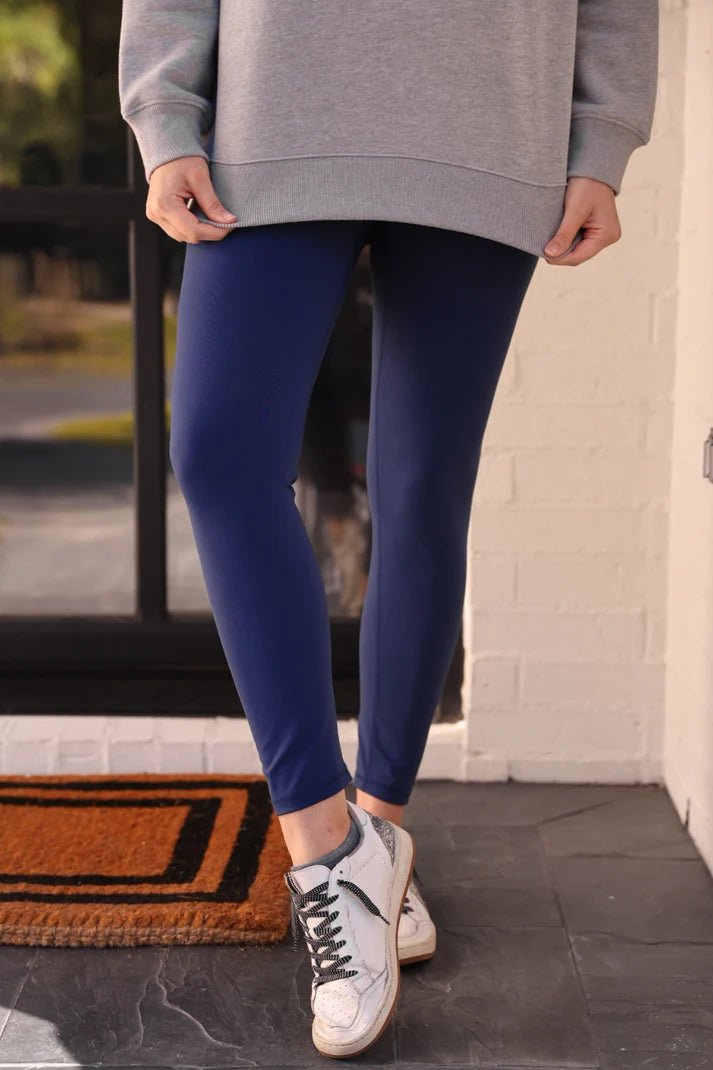 Woman wearing navy compression leggings with a gray sweatshirt and tennis shoes.