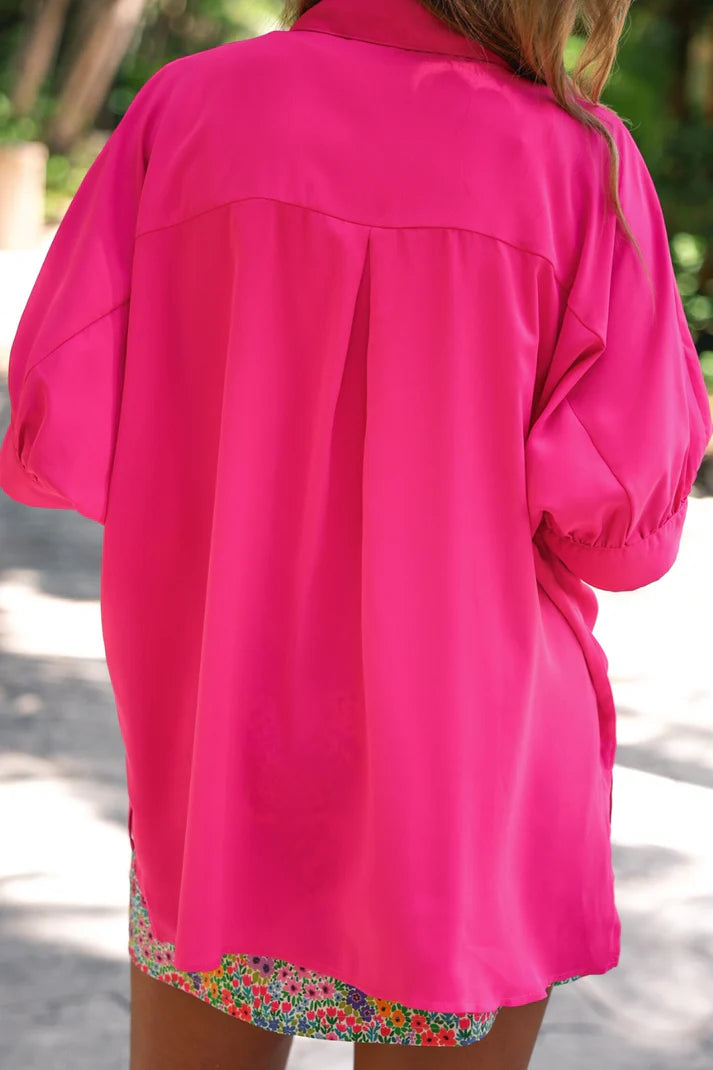 Person wearing a bright pink jacket with a blurred natural background